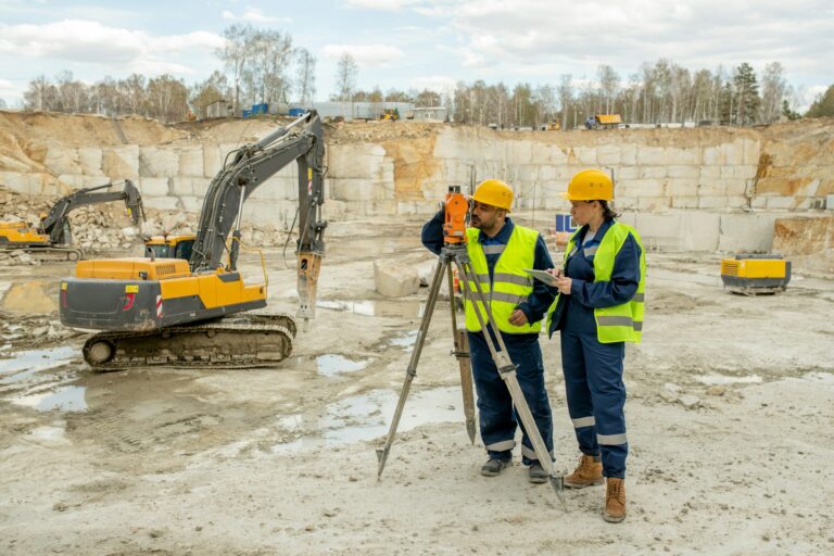 Male and female surveyors working on construction site